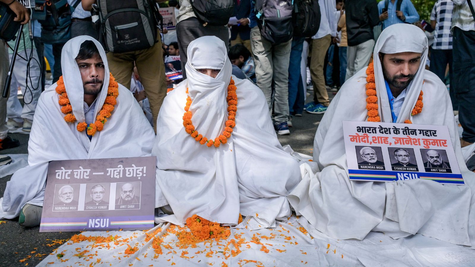 NSUI national president Vinod Jakhar, right, along with members wrapped in white sheets and holding placards stage a protest. Photo: PTI